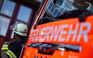 Feuerwehrmann steht neben einem Feuerwehrauto (Symbolbild)