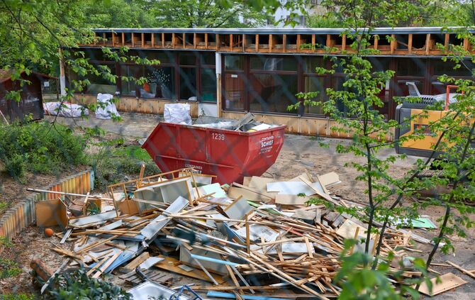 Blick durch den Maschendrahtzaun, der das alte Körnle-Kindergarten-Areal einfasst: Über die entsorgten Möbel regt sich eine Bürg