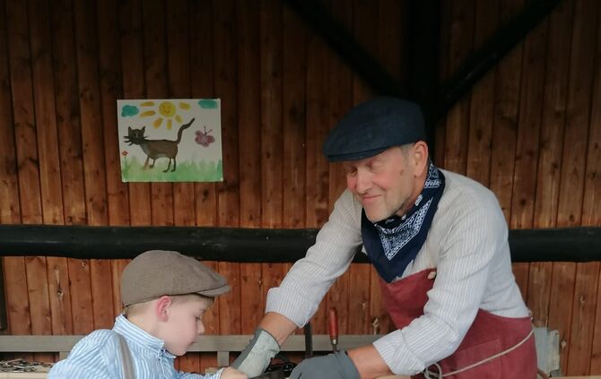 Ein Junge lernt das Sägen bei einer Handwerksvorführung im Dorf- und Heimatmuseum Winterbach.