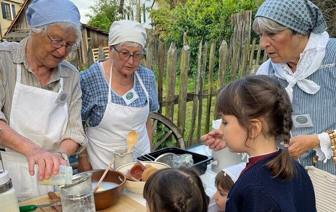 Mitglieder des Heimatvereins Winterbach zeigen Kindern die traditionelle Butterherstellung am Dorf- und Heimatmuseum.