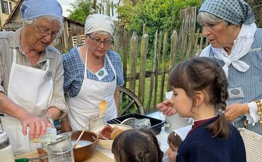 Mitglieder des Heimatvereins Winterbach zeigen Kindern die traditionelle Butterherstellung am Dorf- und Heimatmuseum.