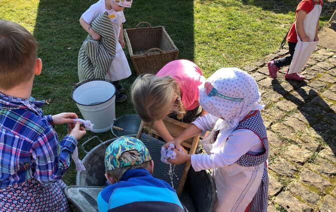 Kinder lernen das Wäschewaschen mit Waschbrett und Zinkwanne im Dorf- und Heimatmuseum Winterbach.
