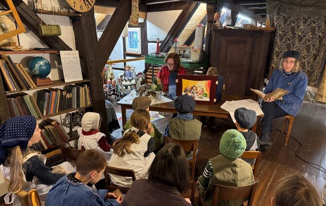 Vorlesestunde: Kinder in historischer Kleidung lauschen einer Vorlesestunde im Dorf- und Heimatmuseum Winterbach.