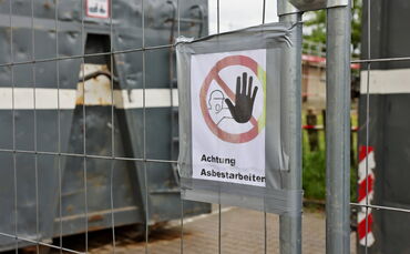 Ein Schild am Bauzaun der Baustelle warnt vor den aktuell noch laufenden Arbeiten, die eine Fachfirma ausführt.