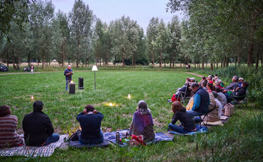Besucher lauschen einer Lesung in der Kunstlichtung in der Talaue Waiblingen.