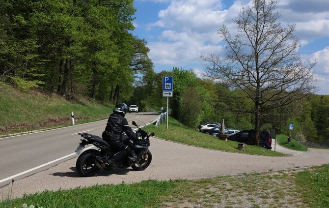 Ein Motoradfahrer fährt im Frühjahr 2026 auf den Parkplatz zwischen Schnait und Manolzweiler.