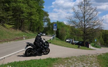 Ein Motoradfahrer fährt im Frühjahr 2026 auf den Parkplatz zwischen Schnait und Manolzweiler.