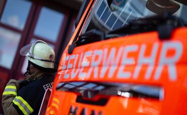 Feuerwehrmann steht neben einem Feuerwehrauto (Symbolbild)
