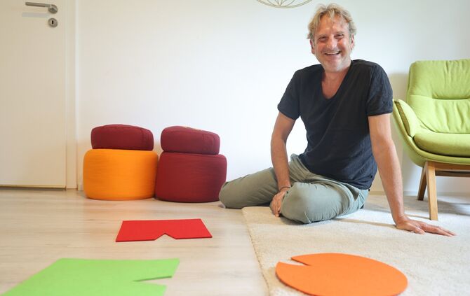 Michael Joos sitzt vor bunten Filzstücken: Er erklärt, was diese Hilfsmittel bei einem Burnout aufzeigen können.