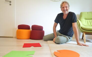 Michael Joos sitzt vor bunten Filzstücken: Er erklärt, was diese Hilfsmittel bei einem Burnout aufzeigen können.