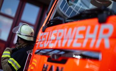 Feuerwehrmann steht neben einem Feuerwehrauto (Symbolbild)
