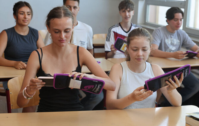 Die Schülerinnen und Schüler der Klasse 11a zeigen, wie es funktioniert: Zu Unterrichtsbeginn müssen sie ihre Smartphones in die