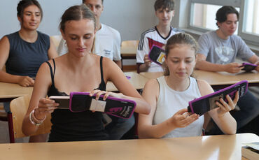 Die Schülerinnen und Schüler der Klasse 11a zeigen, wie es funktioniert: Zu Unterrichtsbeginn müssen sie ihre Smartphones in die