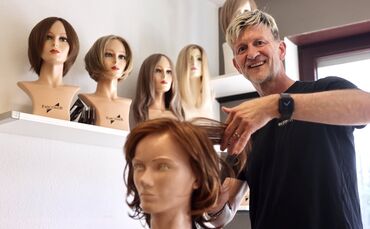 Friseurmeister Kai Schäftlmeier bei der Arbeit an einer Perücke.