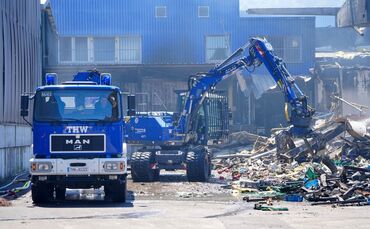 Einsatzkräfte des Technischen Hilfswerks (THW) beseitigen mit einem Bagger Schutt nach einem Feuer in einem Gewerbegebiet in Stu