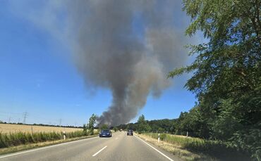 Eine Rauchsäule steigt am Fahrbahnrand der B36 in Linkenheim-Hochstetten auf.