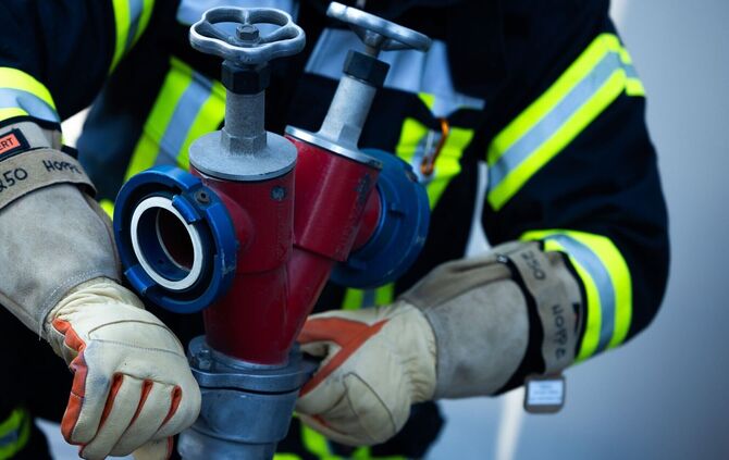 Feuerwehrleute verhindern ein Übergreifen der Flammen auf andere Gebäude. (Symbolbild)