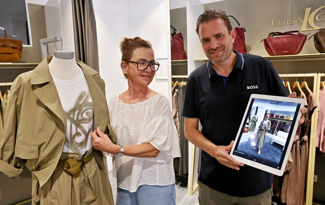 Christian Hartmann, Inhaber von Mode am Markt, zeigt auf dem iPad, wie ein Kleidungsstück aus seinem Geschäft (links) an seiner