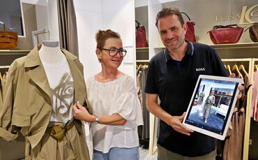 Christian Hartmann, Inhaber von Mode am Markt, zeigt auf dem iPad, wie ein Kleidungsstück aus seinem Geschäft (links) an seiner