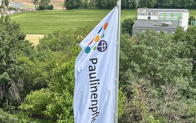 Burgführer in historischen Kostümen vor der Paulinenpflege-Fahne auf Burg Reichenberg.