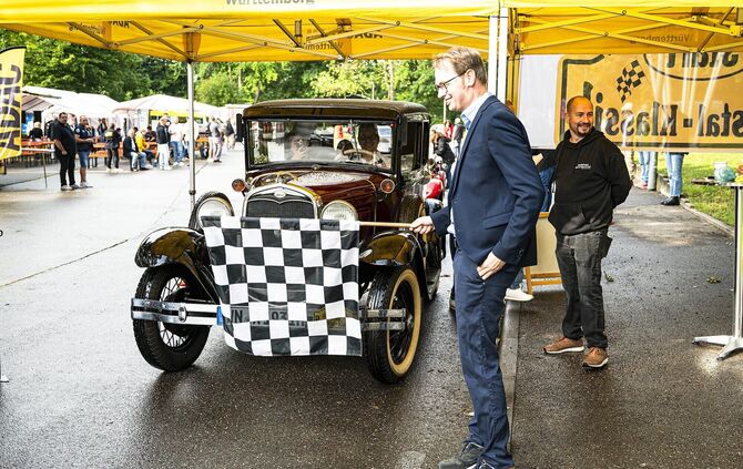 Ein Oldtimer wird bei der Remstal-Klassik mit der Zielflagge empfangen.
