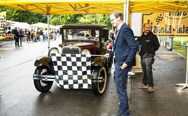 Ein Oldtimer wird bei der Remstal-Klassik mit der Zielflagge empfangen.