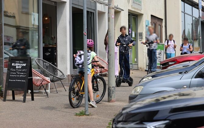 Der enge Gehweg an der Paulinenstraße zwischen "Glückskind" und "Skurril": Ein Radler bergauf, zwei E-Scooter bergab. Kinder bis