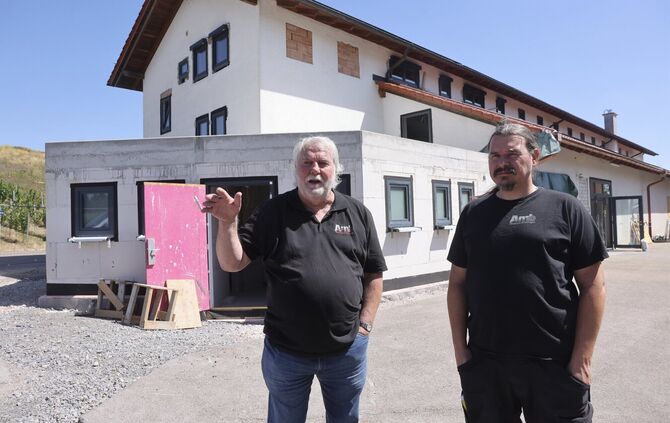 Manfred  (links) und Markus Amberger im Hof der Kelter mit ihrem Anbau für die Toiletten.