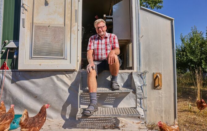 Er hat viele verschiedene Tiere: Landwirt Berthold Czycholl sitzt bei seinen Hühnern.