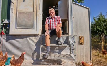 Er hat viele verschiedene Tiere: Landwirt Berthold Czycholl sitzt bei seinen Hühnern.