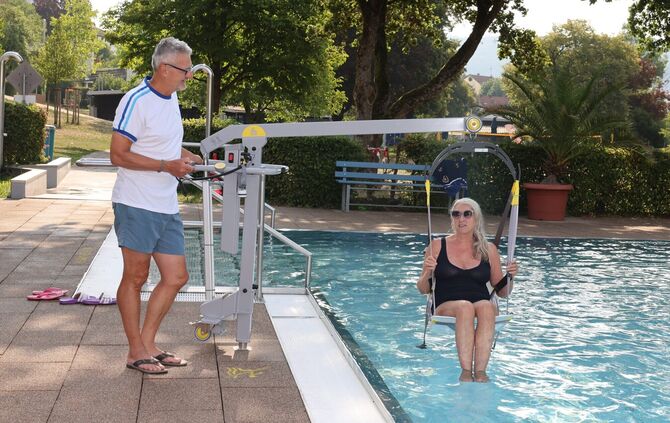 Ganz schön entspannt: Uli Netzer vom Freibadförderverein, wie er Badegast Kornelie Krause zum Test ins Wasser hievt.