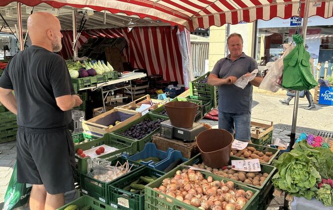 Harald Maier (rechts) verkauft Gemüse, Obst und Eier auf dem Wochenmarkt. Unter seinem Schirm staut sich die Hitze.