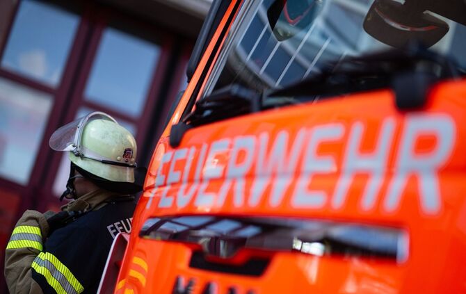 Feuerwehrmann steht neben einem Feuerwehrauto (Symbolbild)