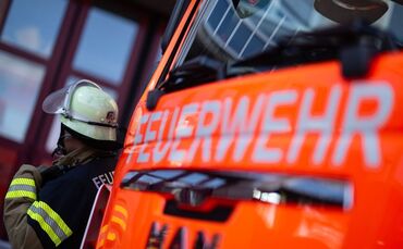 Feuerwehrmann steht neben einem Feuerwehrauto (Symbolbild)