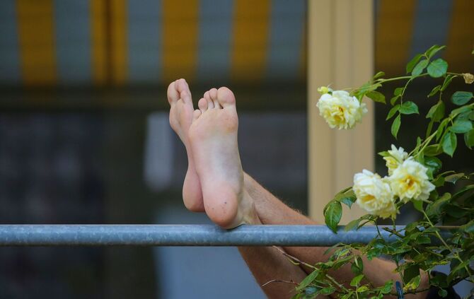Die Füße eines Mannes sind auf einem Balkon zu sehen