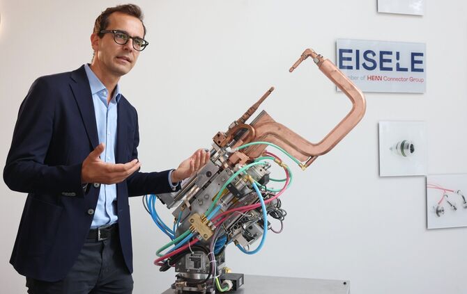 Eisele-Geschäftsführer Johannes Jeitler vor einer Punktschweißzange, in welche Anschlüsse des Unternehmens eingebaut sind. Künft