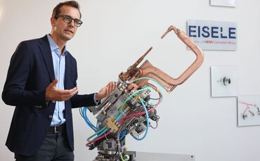 Eisele-Geschäftsführer Johannes Jeitler vor einer Punktschweißzange, in welche Anschlüsse des Unternehmens eingebaut sind. Künft