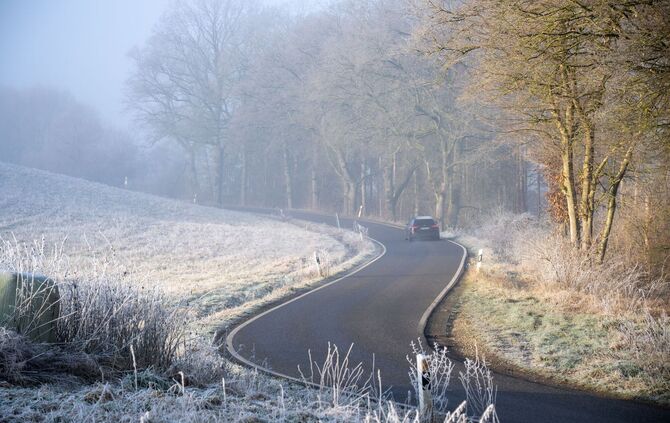 Auto fährt durch eine frostige Landschaft.