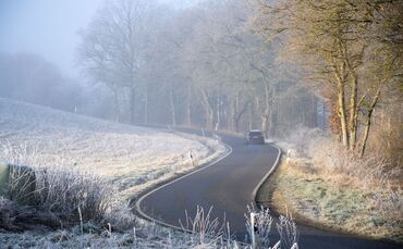 Auto fährt durch eine frostige Landschaft.
