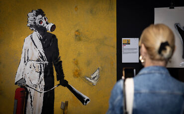 Das Original-Graffiti "Frau mit Gasmaske" ist in der Ukraine an einer Wand von Banksy gesprüht worden.