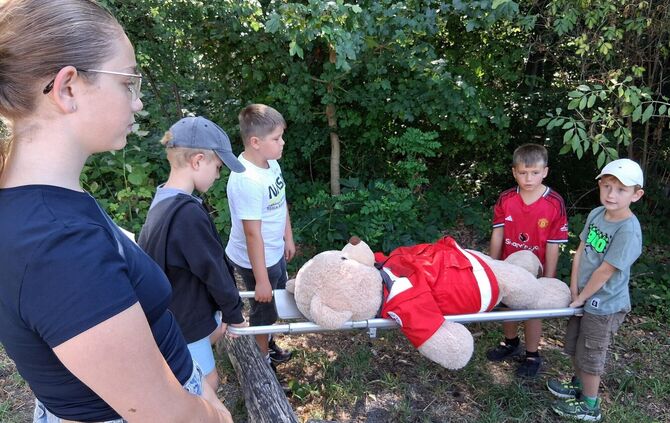 Maja heißt der Teddy, der so schlapp auf der Liege liegt und vom Rot-Kreuz-Nachwuchs fachmännisch transportiert wird.