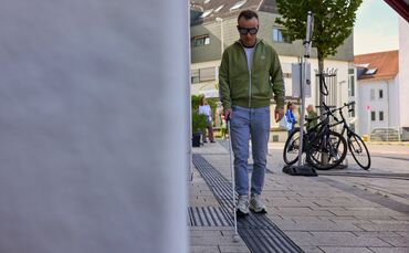 Redakteur Tobias Klecker, ausgestattet mit Blindenstock und einer Brille, die Blindheit simuliert.