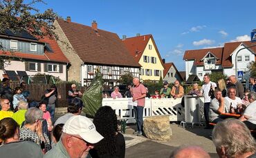 Überraschung: Noch ist der Brunnen verborgen, die Gäste warten gespannt auf die Enthüllung.
