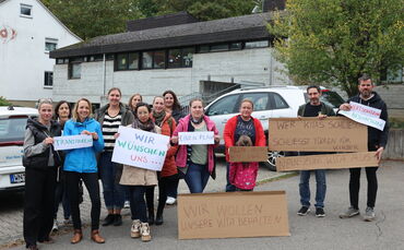 "Wir wollen unsere Kita behalten": Mit Plakaten protestieren Eltern gegen die geplante Schließung des katholischen Kindergartens