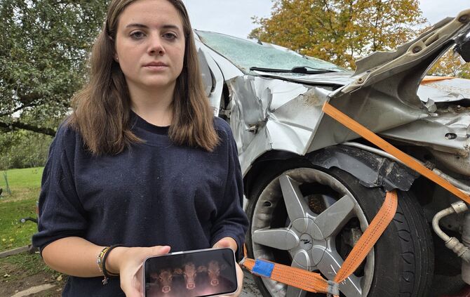 Stephanie Schuhmann neben dem Unfallauto – das Bild auf dem Handy ist Verbildlichung ihrer Erinnerung an die Kuhköpfe, die plötz