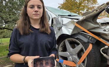 Stephanie Schuhmann neben dem Unfallauto – das Bild auf dem Handy ist Verbildlichung ihrer Erinnerung an die Kuhköpfe, die plötz