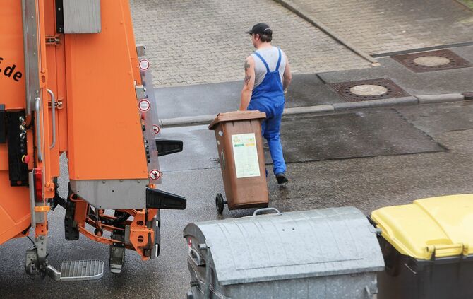 Ein Müllwerker mit einer braunen Biomülltonne (Symbolfoto).